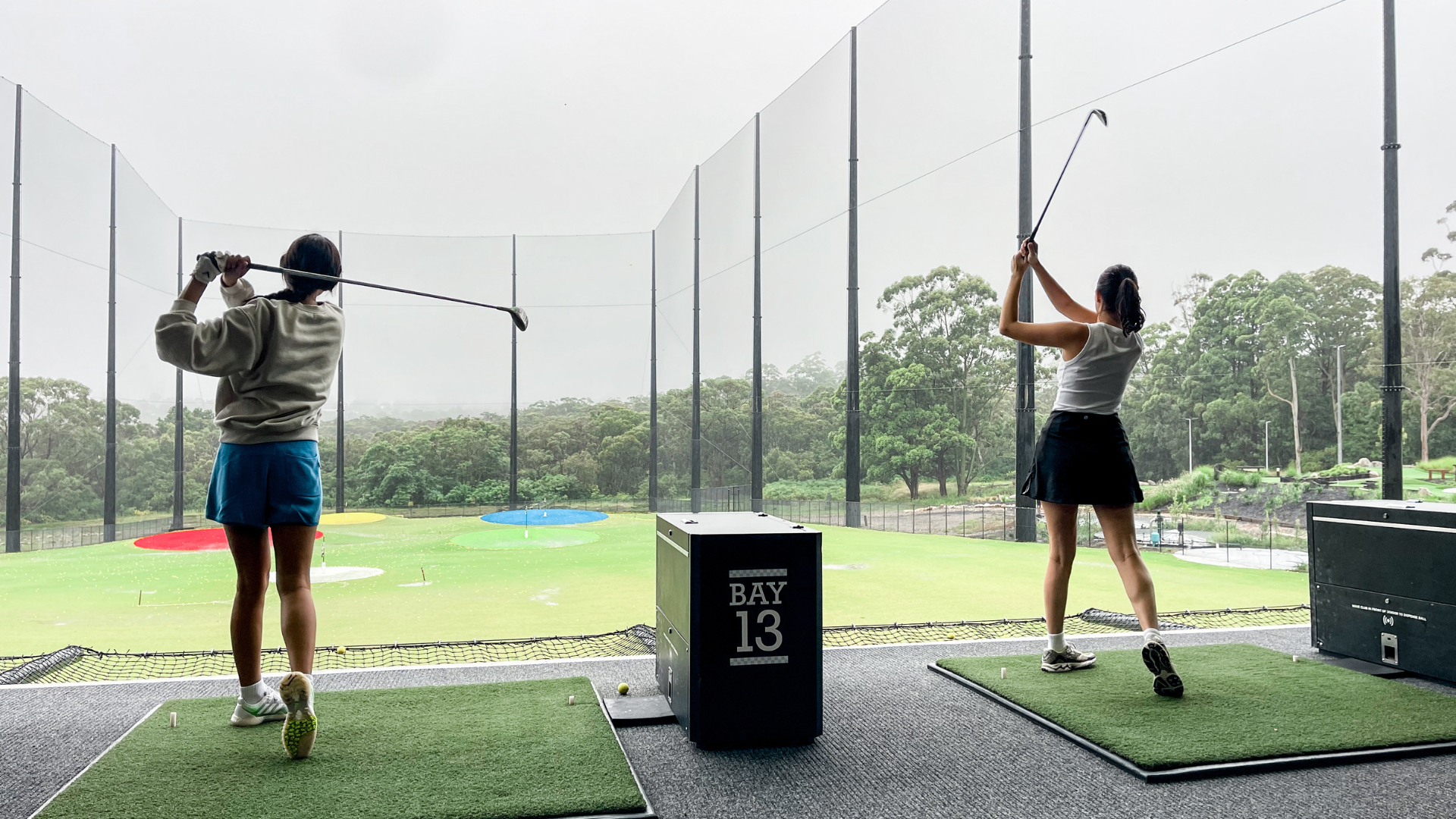 Two girls swinging their clubs together at the same time